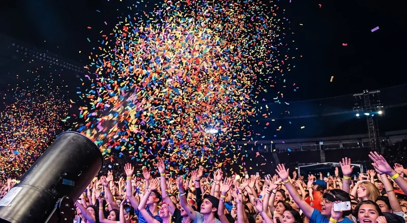 Máquina lanza papel disparando confeti sobre el público en un concierto