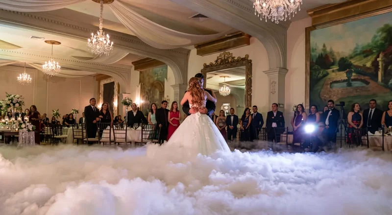 Novios en su primer baile flotando sobre una densa capa de humo bajo en un salón con candelabros