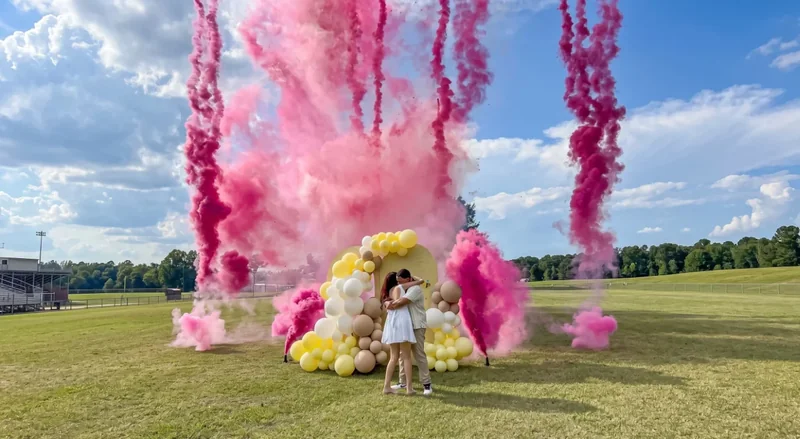 Revelación de género al aire libre con múltiples columnas de humo rosa junto a un arco de globos