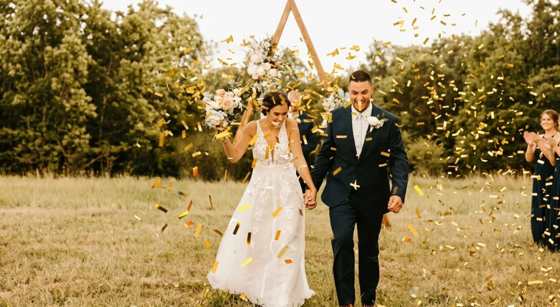 Cañón de confeti con confeti dorado en la salida de una boda al aire libre