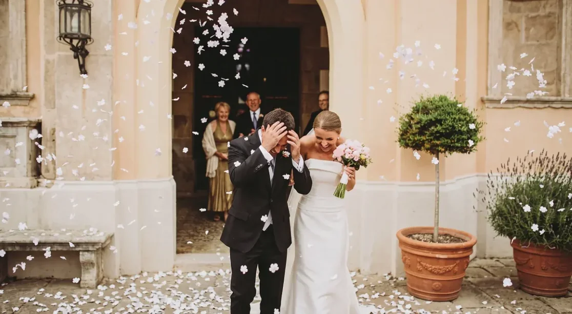 Novios saliendo de la ceremonia entre una lluvia de pétalos