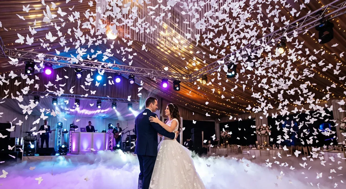 Primer baile bajo una cascada de mariposas de papel blancas colgando del techo