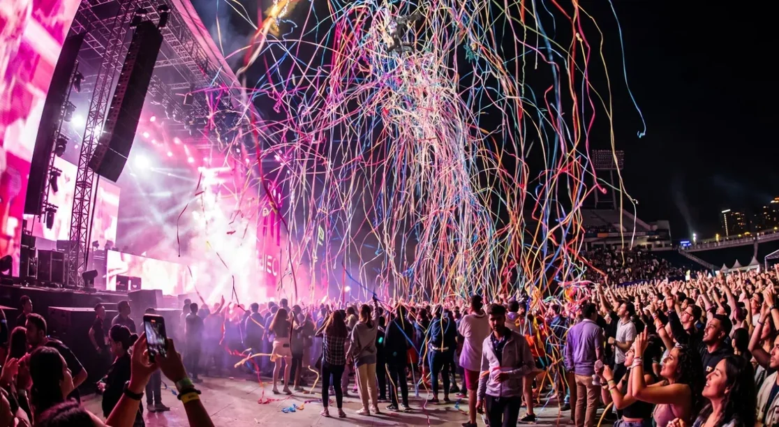 Serpentinas de colores disparadas hacia el cielo sobre el público en un festival nocturno