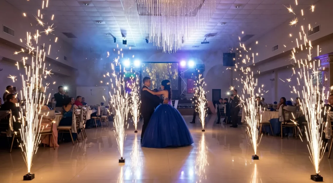 Vals de XV años en un salón interior con candelabro, entre múltiples fuentes de chispa fría a cada lado de la pista